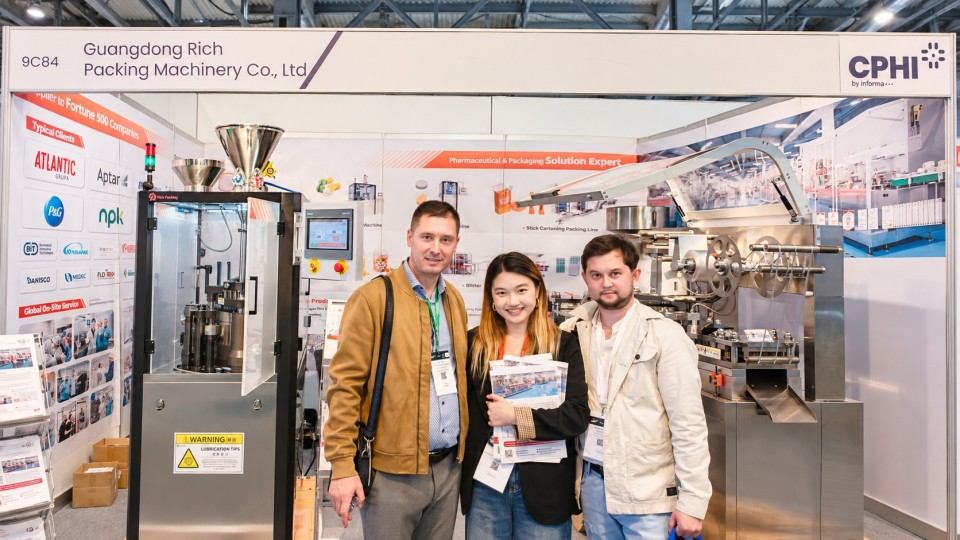 Visitors with a Rich Packing representative beside the displayed pharmaceutical machinery